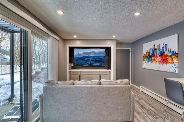 home theater room with baseboards, a baseboard radiator, wood finished floors, a textured ceiling, and recessed lighting