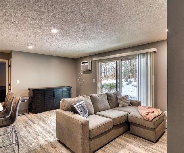 living room with an AC wall unit and light wood-style flooring