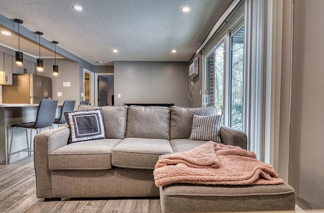 living room featuring light wood-type flooring, a textured ceiling, and recessed lighting