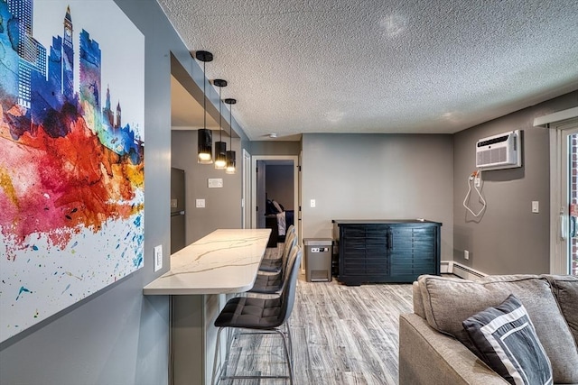 kitchen featuring light wood-style flooring, open floor plan, baseboard heating, a textured ceiling, and an AC wall unit