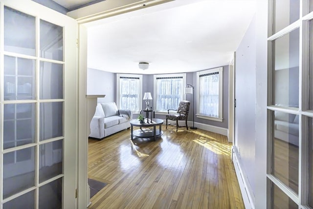 living room featuring a baseboard heating unit, baseboards, and hardwood / wood-style flooring