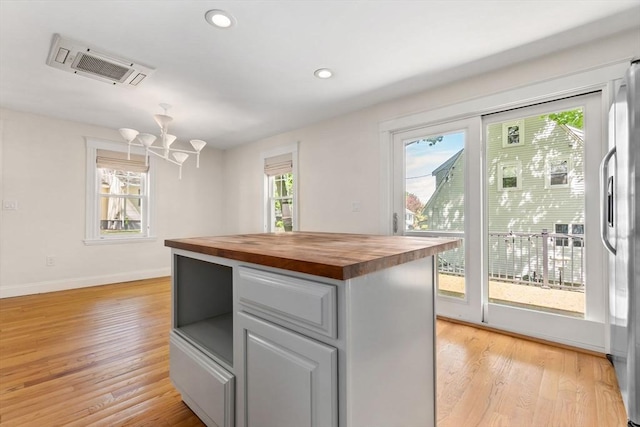 46 Leonard St, Woburn, MA 01801 - kitchen with wooden counters, stainless steel fridge, light wood-type flooring, a chandelier, and baseboards