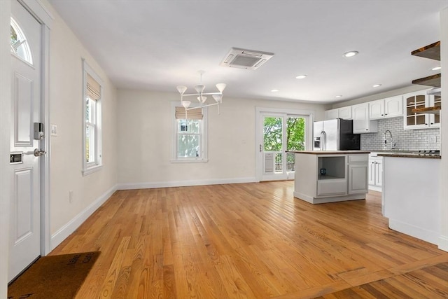 46 Leonard St, Woburn, MA 01801 - kitchen featuring fridge with ice dispenser, light wood finished floors, white cabinetry, tasteful backsplash, and a chandelier