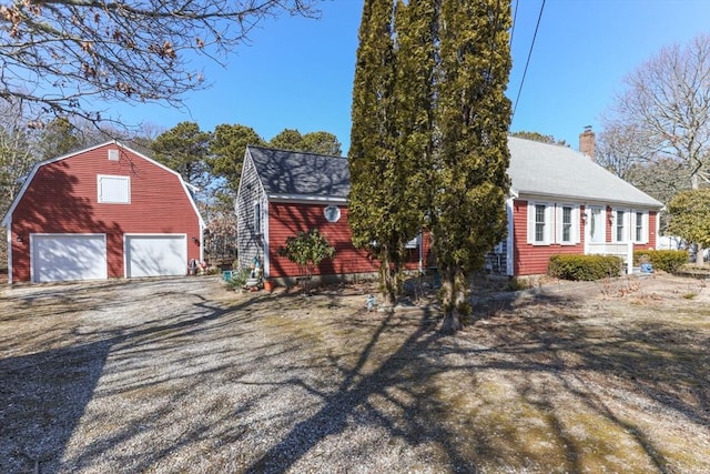 125 Wamsutta Rd, Eastham, MA 02642 - view of front of home featuring a garage, an outbuilding, a chimney, and gravel driveway