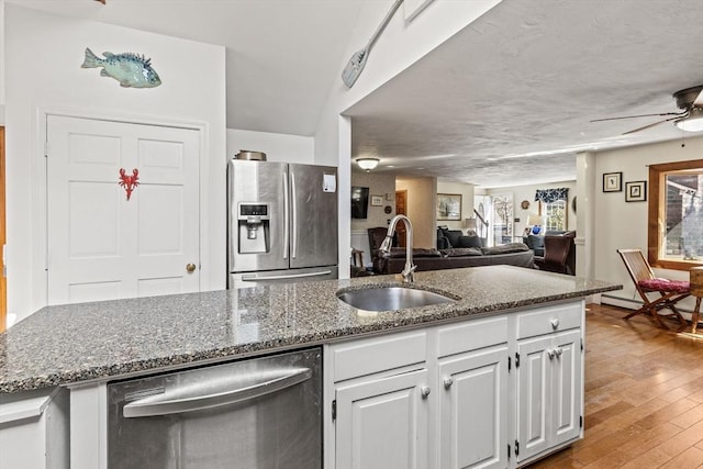 125 Wamsutta Rd, Eastham, MA 02642 - kitchen featuring stainless steel appliances, a sink, a ceiling fan, light wood finished floors, and dark stone countertops