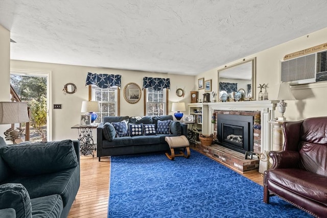 125 Wamsutta Rd, Eastham, MA 02642 - living area featuring wood finished floors, a fireplace, a wall unit AC, and a textured ceiling