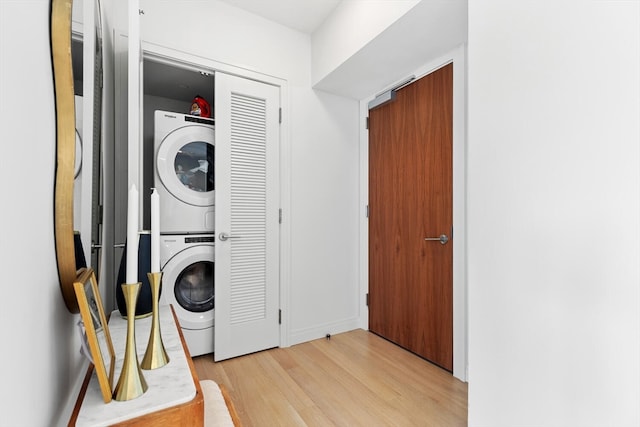 laundry room featuring light wood-type flooring and stacked washer and dryer