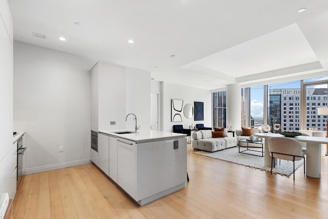 kitchen with white dishwasher, light hardwood / wood-style floors, sink, stainless steel oven, and kitchen peninsula