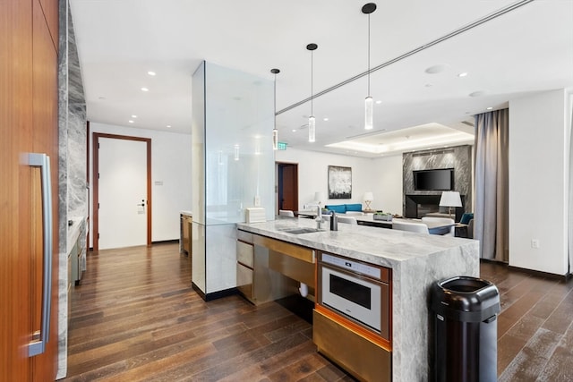 kitchen with a tray ceiling, hanging light fixtures, dark hardwood / wood-style floors, and sink