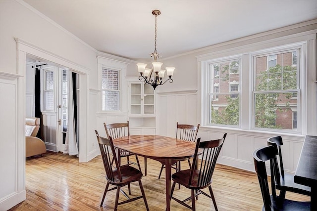 34 Garrison Rd Unit 4, Brookline, MA 02445 - dining area featuring a decorative wall, light wood-type flooring, a chandelier, wainscoting, and ornamental molding