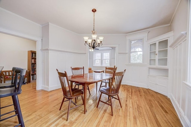 34 Garrison Rd Unit 4, Brookline, MA 02445 - dining space with a chandelier, a decorative wall, light wood-style flooring, wainscoting, and crown molding