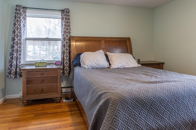 bedroom featuring baseboard heating and light hardwood / wood-style floors