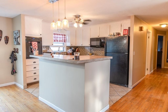 kitchen with white cabinetry, a center island, black appliances, decorative backsplash, and decorative light fixtures