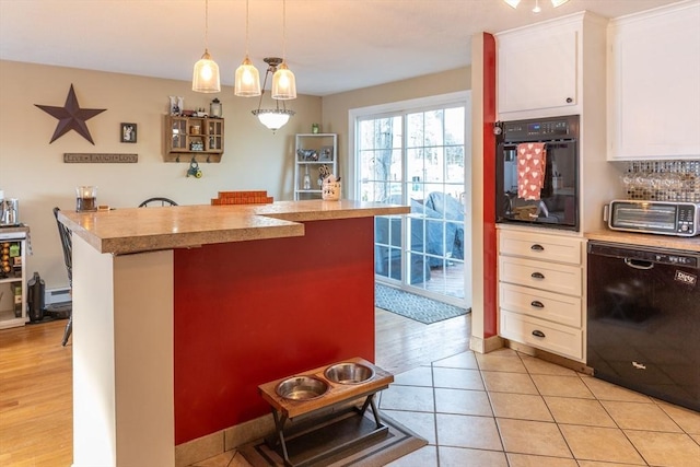 kitchen with a kitchen bar, white cabinetry, decorative light fixtures, light tile patterned floors, and black appliances