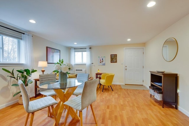 dining space featuring a wall mounted air conditioner and light wood-type flooring