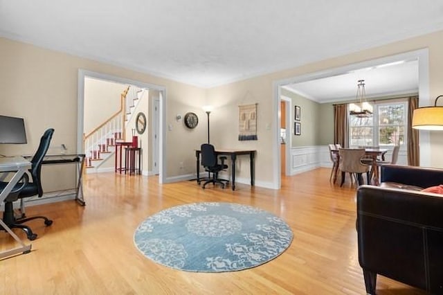 living area with stairs, wood finished floors, a notable chandelier, and a wainscoted wall