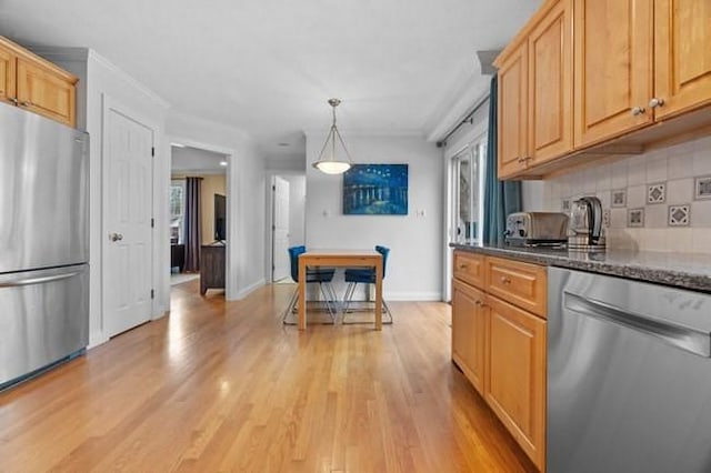 kitchen featuring light wood-style floors, baseboards, dark stone counters, appliances with stainless steel finishes, and backsplash