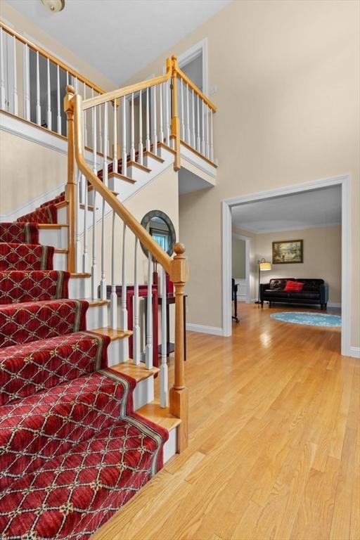 stairway featuring baseboards, a high ceiling, and wood finished floors