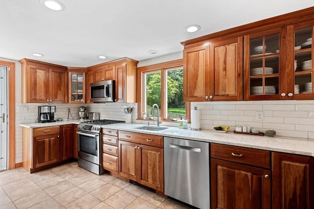 37 Berkeley Dr, Falmouth, MA 02536 - kitchen featuring appliances with stainless steel finishes, backsplash, light tile patterned floors, brown cabinetry, and light stone counters