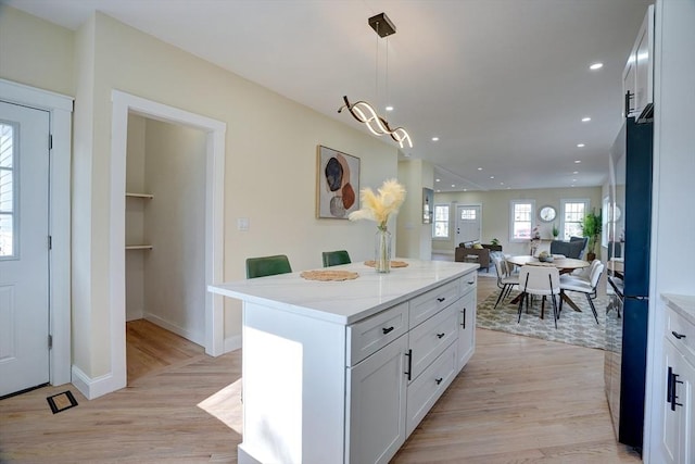 kitchen featuring a kitchen island, light wood-style floors, white cabinets, and open floor plan