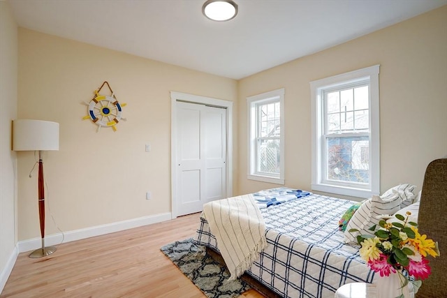 bedroom with a closet, baseboards, and light wood-style flooring