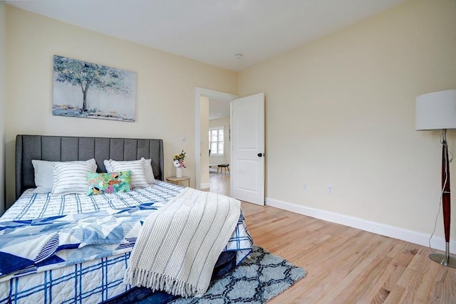 bedroom featuring light wood finished floors and baseboards