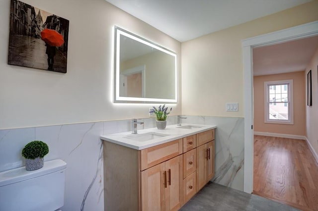 bathroom featuring toilet, wainscoting, and a sink