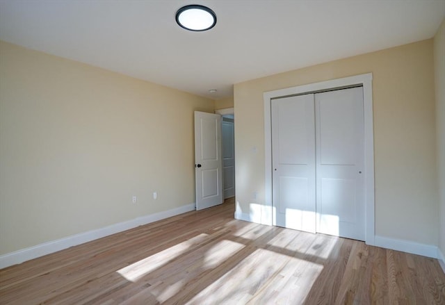 unfurnished bedroom with a closet, light wood-style floors, and baseboards