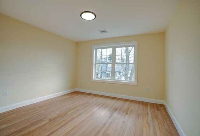 spare room featuring light wood-style flooring, baseboards, and visible vents