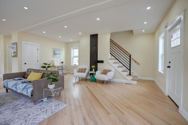 living area with recessed lighting, stairway, baseboards, and light wood-style floors