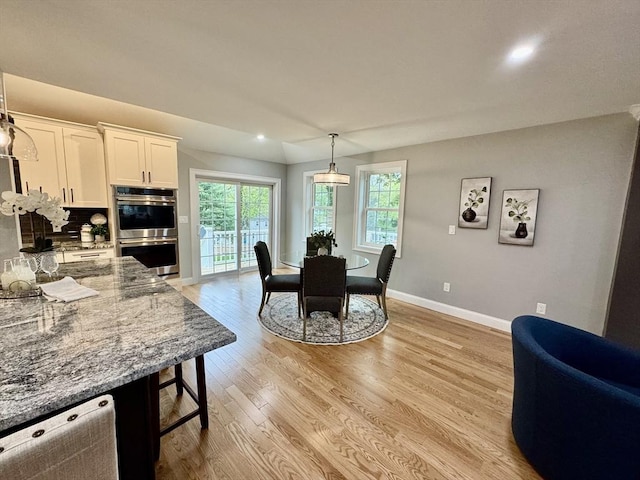 dining space with baseboards, recessed lighting, and light wood finished floors