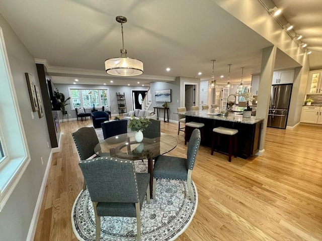 dining space featuring track lighting, baseboards, light wood finished floors, recessed lighting, and crown molding