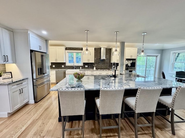 kitchen featuring appliances with stainless steel finishes, a kitchen breakfast bar, tasteful backsplash, light wood-style floors, and recessed lighting