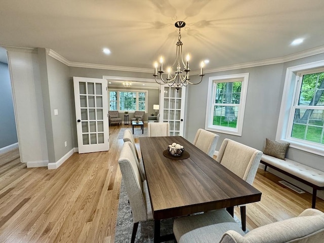 dining area featuring french doors, a chandelier, light wood-style flooring, crown molding, and recessed lighting