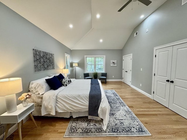 bedroom featuring multiple closets, light wood-style flooring, high vaulted ceiling, baseboards, and recessed lighting