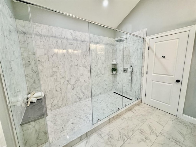 full bath featuring a marble finish shower, marble finish flooring, vaulted ceiling, and baseboards