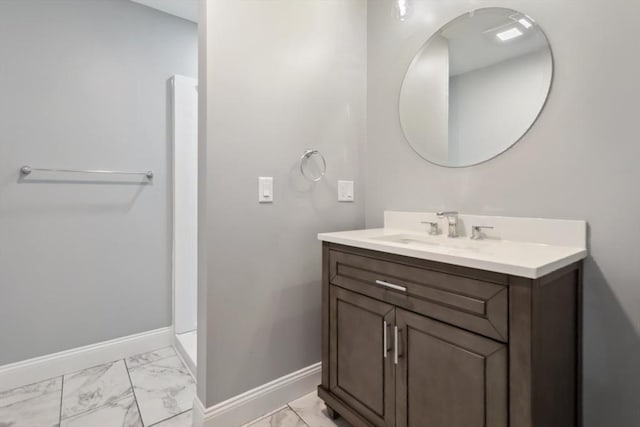 bathroom featuring marble look tile flooring, vanity, and baseboards