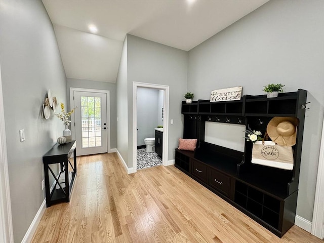 foyer entrance featuring light wood-style floors, vaulted ceiling, and baseboards