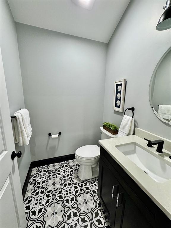 bathroom featuring toilet, vanity, baseboards, and tile patterned flooring