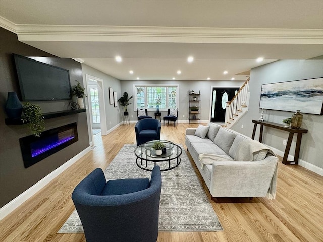 living room featuring stairway, crown molding, baseboards, light wood-style flooring, and a glass covered fireplace