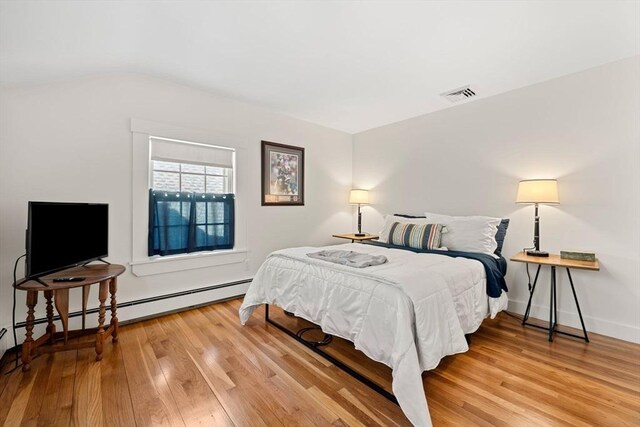 bedroom featuring visible vents, lofted ceiling, baseboards, light wood-style floors, and baseboard heating
