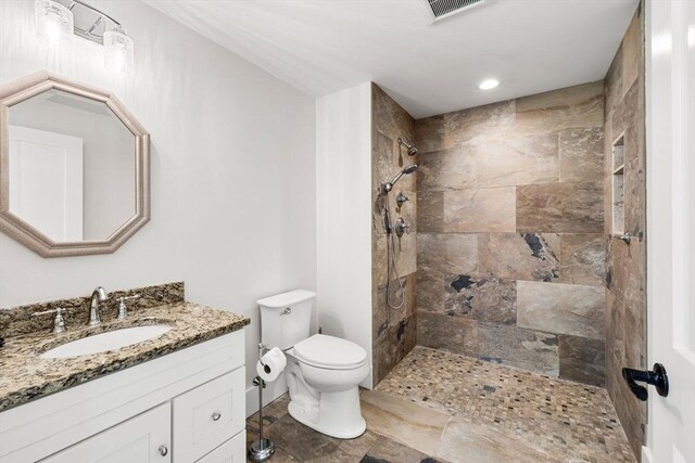 bathroom featuring visible vents, a tile shower, vanity, toilet, and recessed lighting