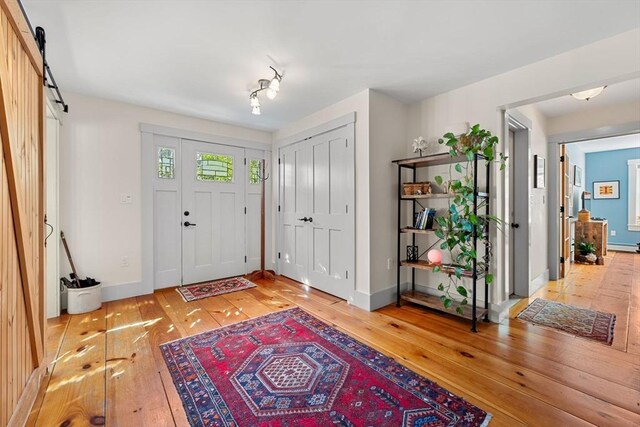 foyer with baseboards, light wood finished floors, and a barn door