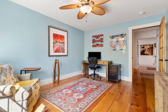 office area with light wood-style floors, baseboards, and a ceiling fan