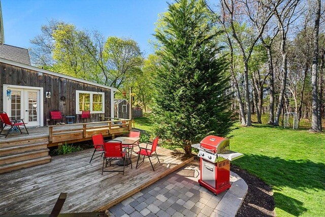 wooden terrace with an outdoor structure, outdoor dining area, area for grilling, a storage unit, and a lawn