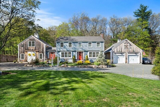 view of front facade with fence, a garage, a front yard, an outbuilding, and a chimney