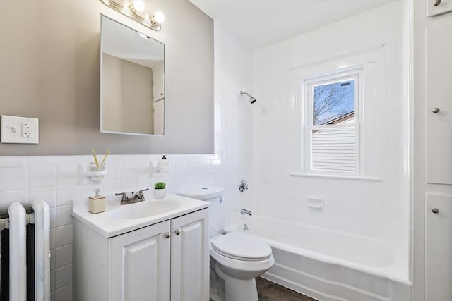 full bathroom featuring radiator, tile walls, vanity, toilet, and tub / shower combination