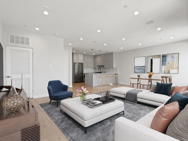 living room with light hardwood / wood-style floors and sink