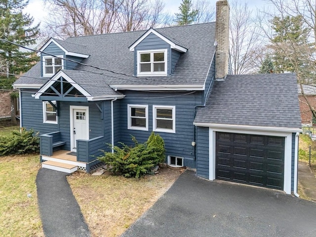 view of front of house with an attached garage, a chimney, a shingled roof, and aphalt driveway