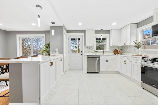 kitchen featuring appliances with stainless steel finishes, a peninsula, white cabinetry, recessed lighting, and tasteful backsplash
